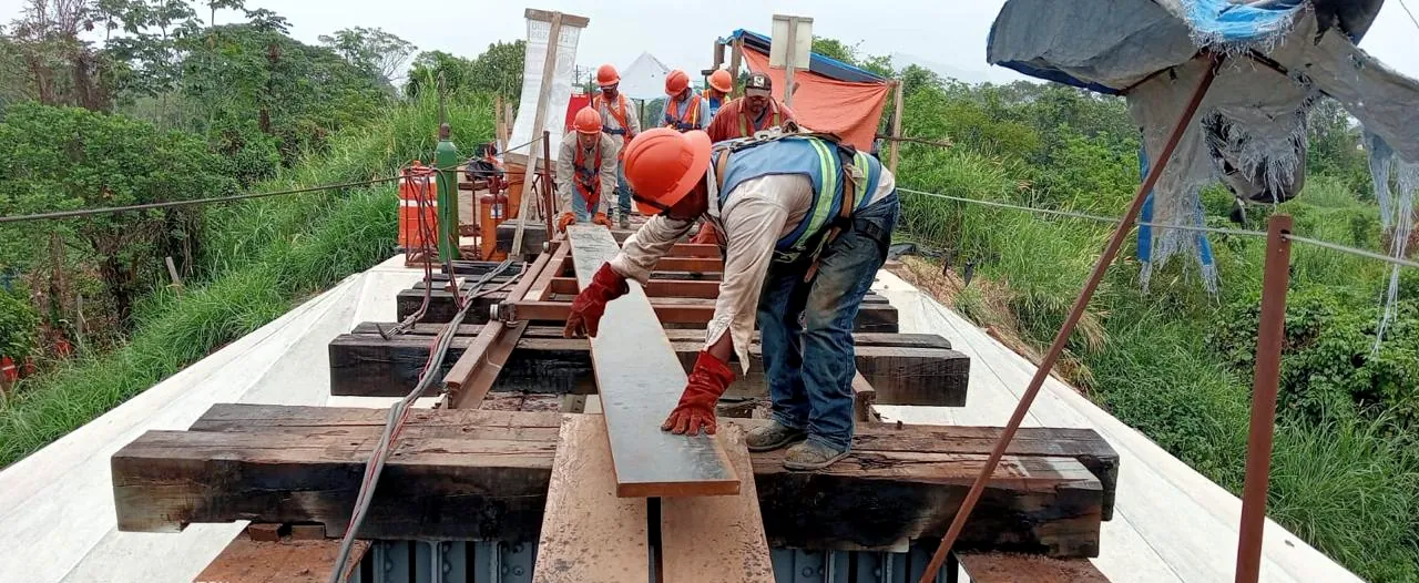 Cuadrilla con equipo de protección trabajando sobre la estructura de un puente ferroviario